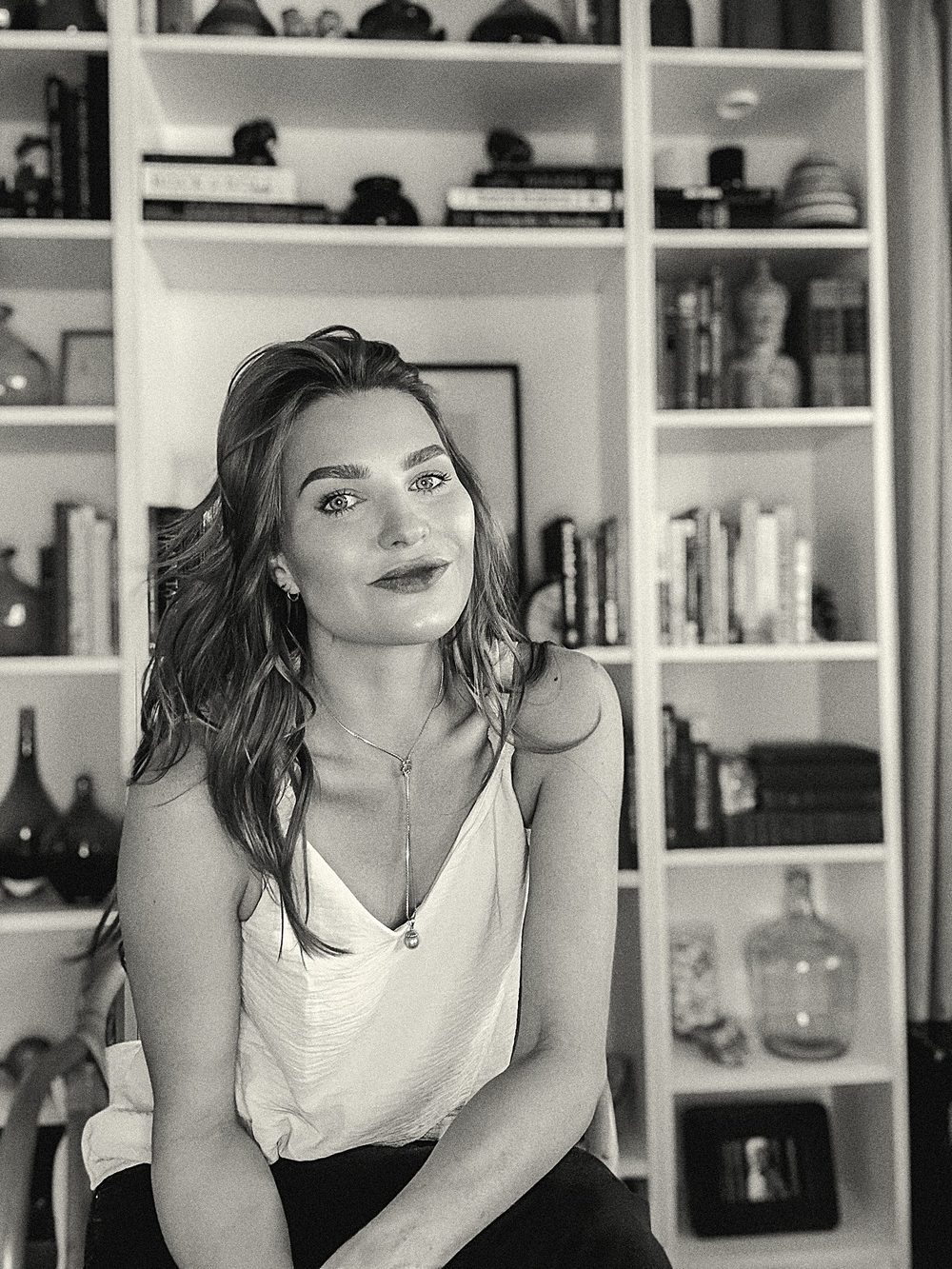 Lauren Florek seated in front of a full bookshelf, a black and white portrait.