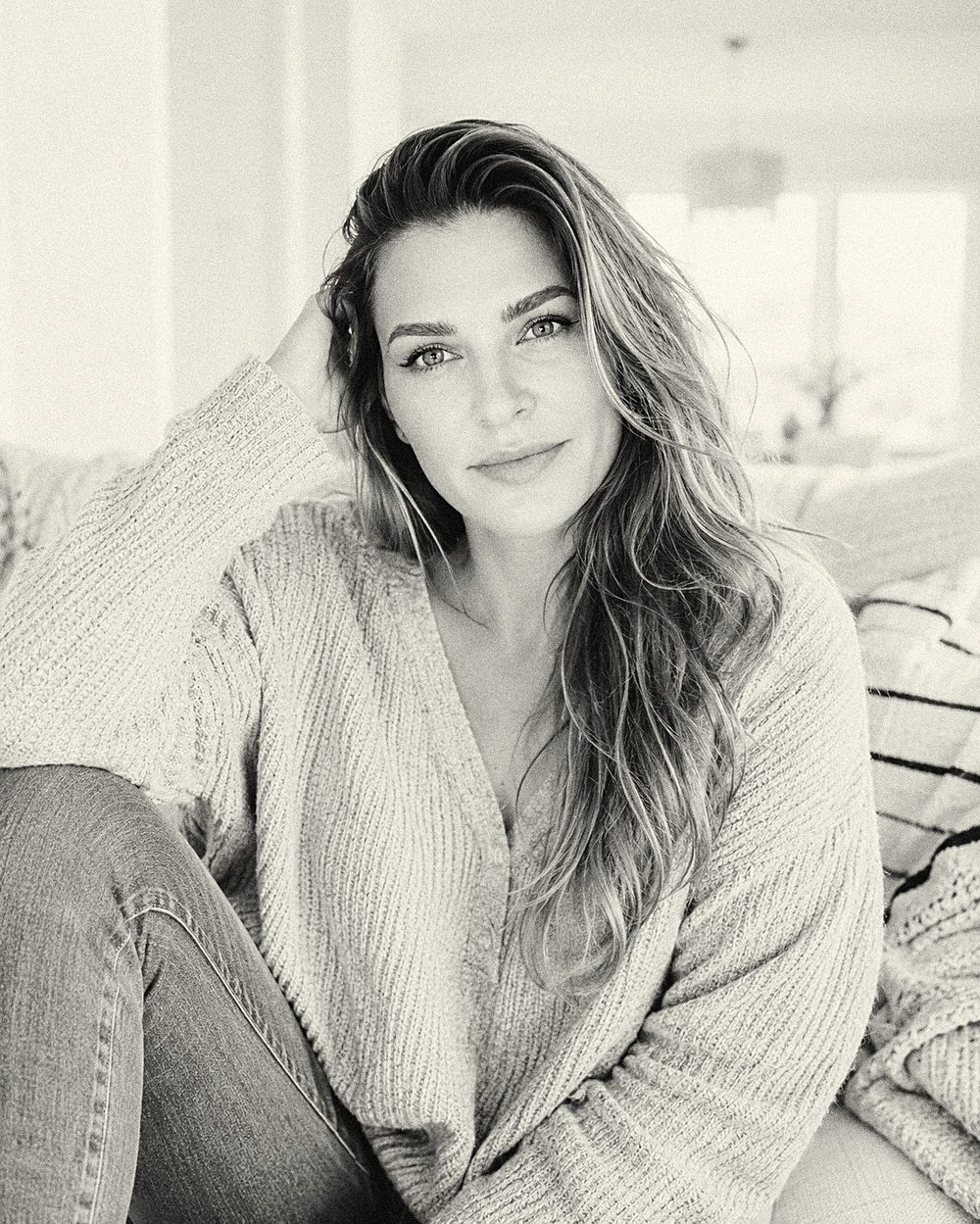 Lauren Florek seated in soft natural light, resting her head on her hand.